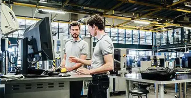 Two people working in front of a screen